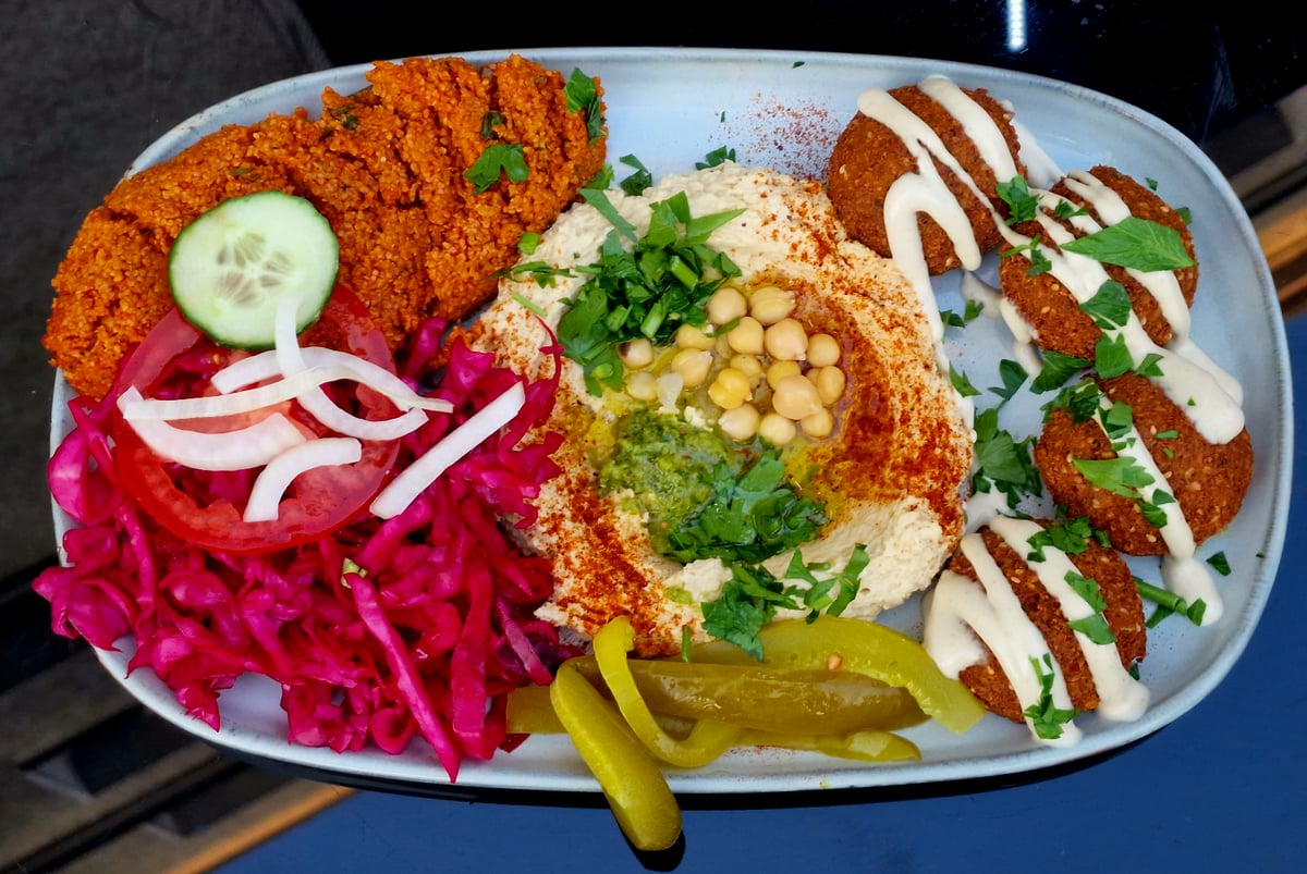 Sült falafelgolyók tányéron, friss zöldségekkel