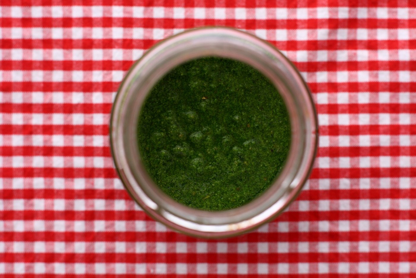 Medvehagyma-pesto befőttesüvegben, felülről, piros kockás terítőn