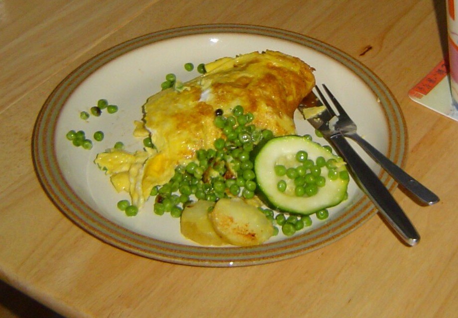Zöldborsós omlett sült burgonyaszeletekkel és friss uborkával, tányéron, otthonos tálalásban